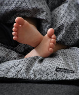 Barnefødder der stikker ud fra sengetøj i farven perfect black